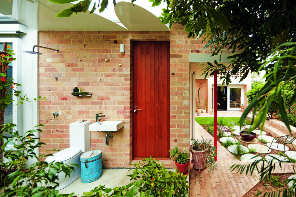 The visual contrast between recycled brick and rendered concrete, complemented by pops of green from the exterior, creates a raw and humbling living environment